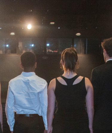 Theater students standing in a semi-circle facing the stage