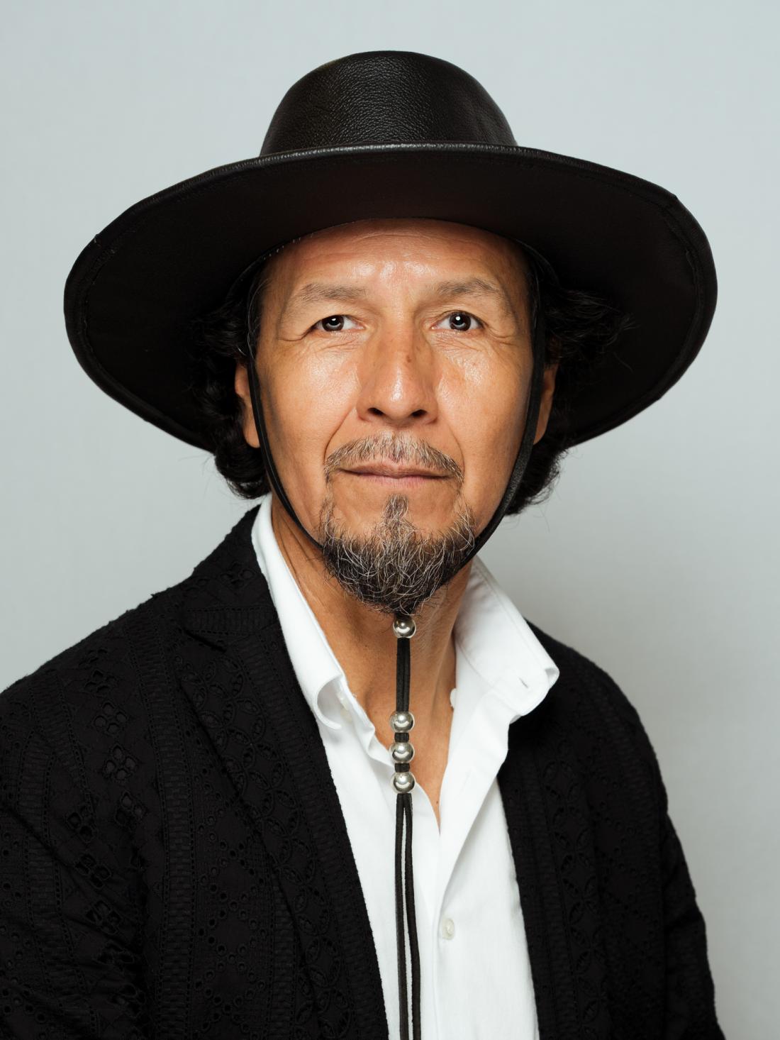 Headshot of Professor Moises Perez wearing a black hat against a white backdrop